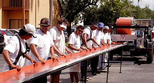 Click image of workers preparing metal roof section to go to Roof Repair Services page.